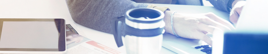 man working on laptop next to ipad and cup of coffee